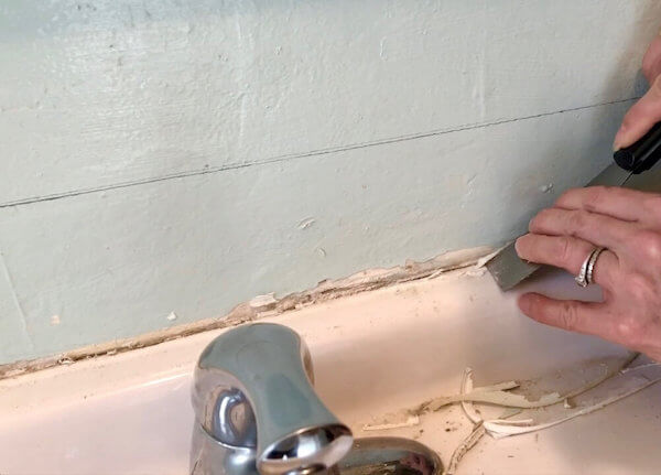 Prep your walls by lightly sanding and scraping off old silicon or grout