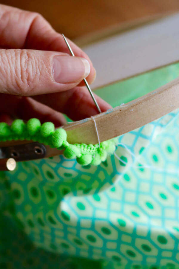 To attach handle, run your needle and thread in and around the top edge of the embroidery hoop. Knot, then do the same on the opposite side