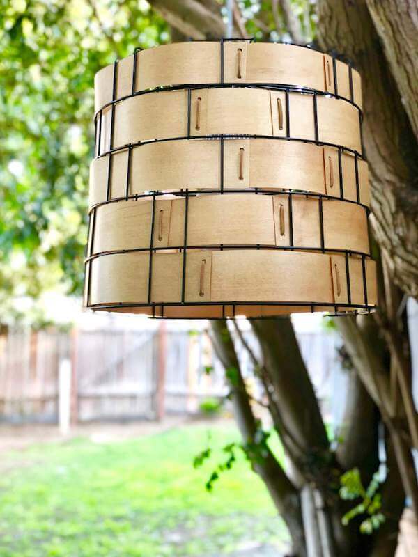 Repurposed metal basket swag light with suede lacing detailing hanging in trees