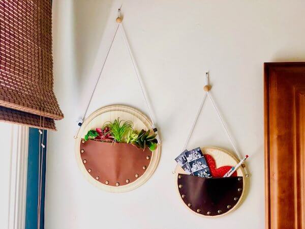 two round leather wall pockets filled with succulents and photos